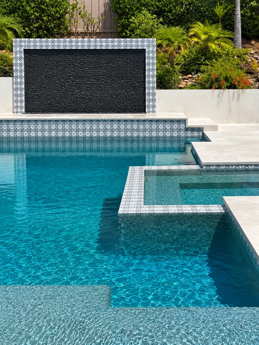 Pool & Spa with Black Pebble Water Wall and Patterned Tile Surround by Moda Outdoor Living in Westlake Village, CA — luxury outdoor living design and build