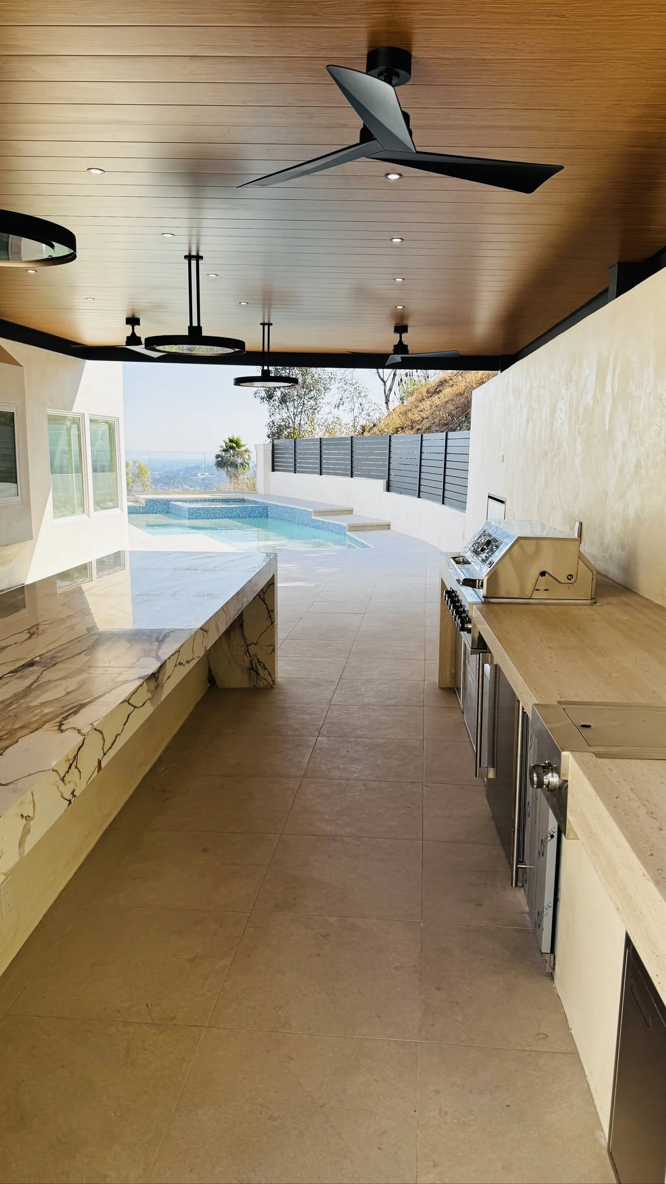 Covered outdoor kitchen with bar seating by Moda Outdoor Living in Glendale, CA — luxury outdoor living design and build