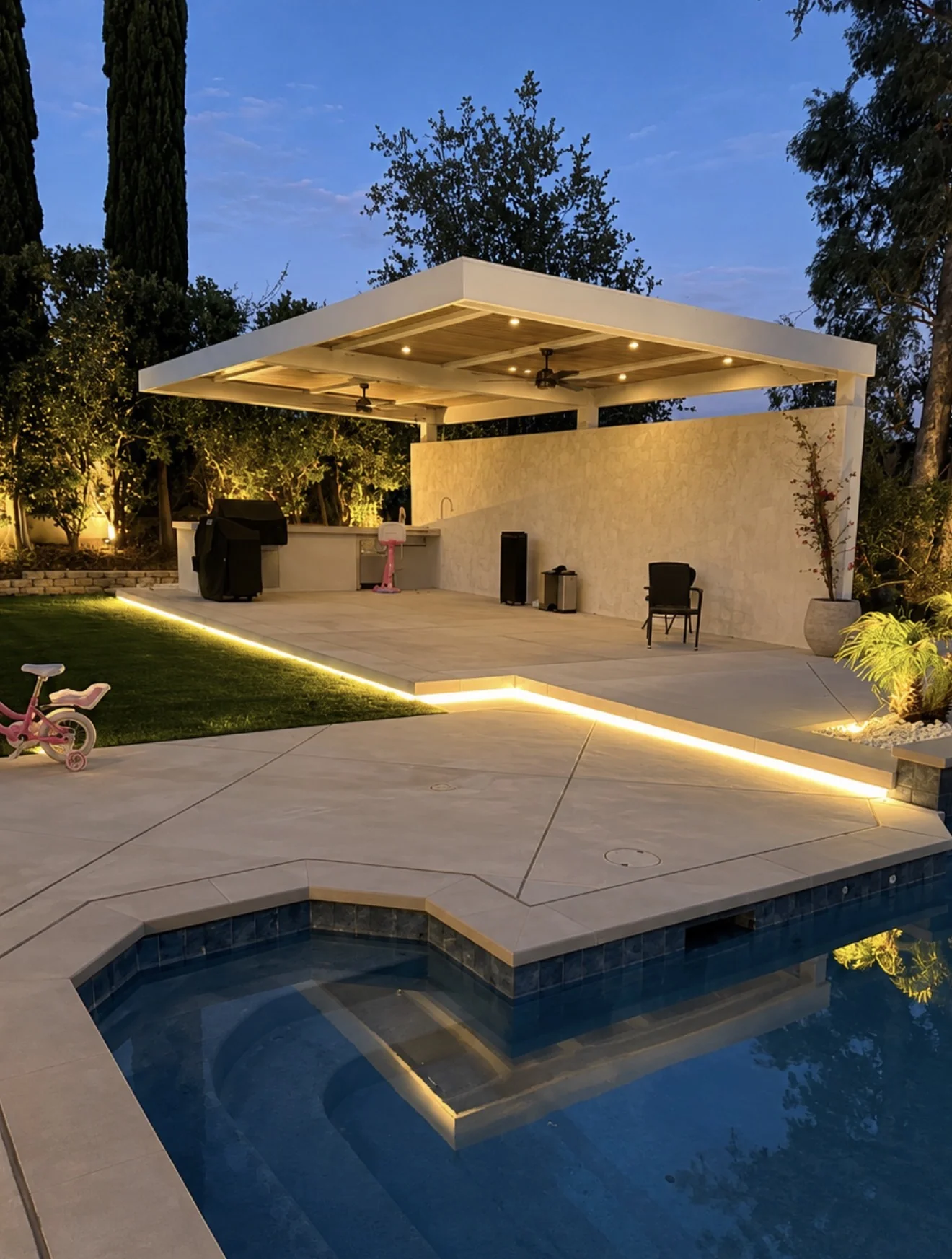 Pergola kitchen and pool glowing at dusk by Moda Outdoor Living in Santa Clarita, CA — luxury outdoor living design and build