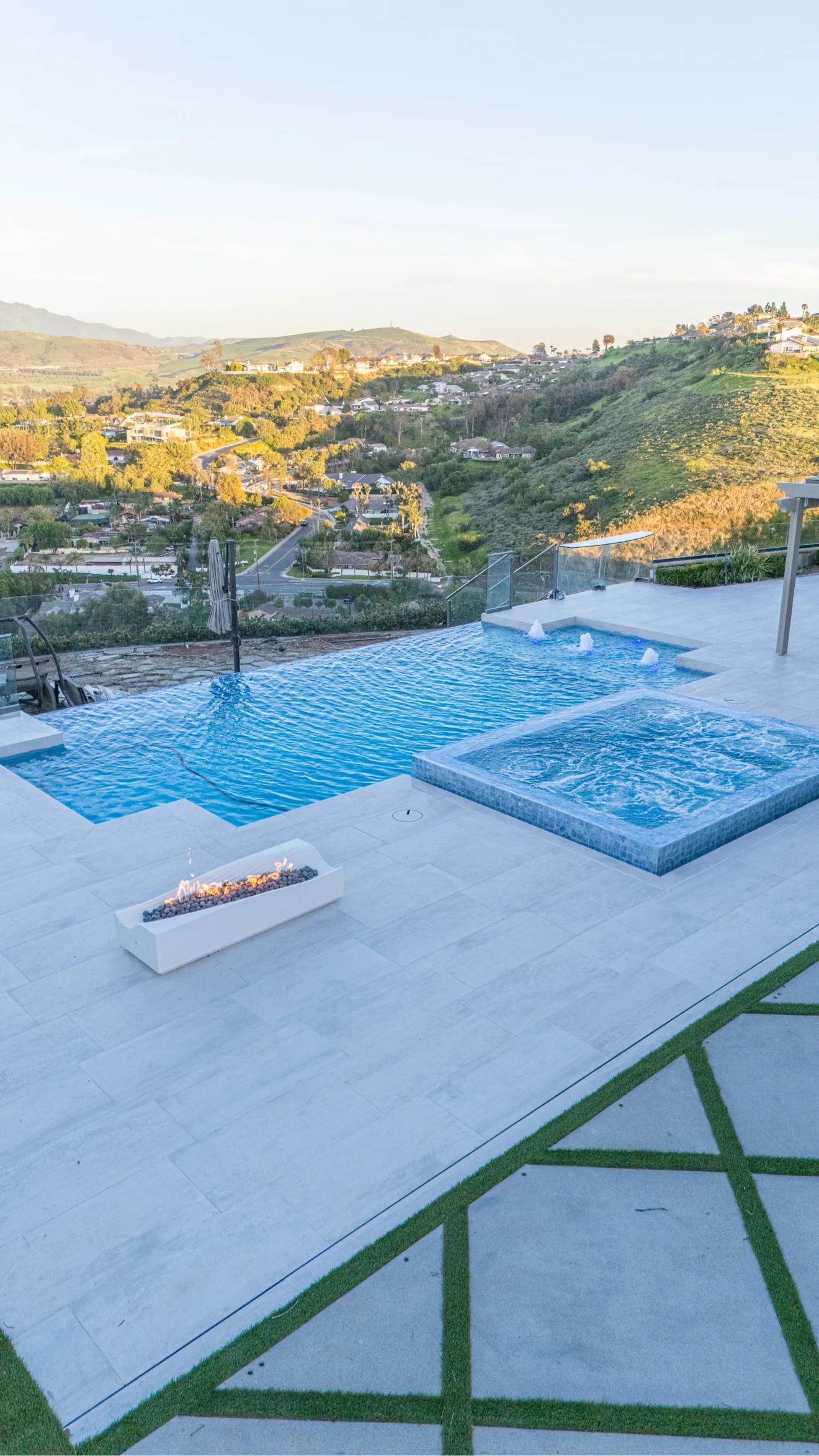 Infinity pool, spa and fire trough at golden hour by Moda Outdoor Living in Orange County, CA — luxury outdoor living design and build