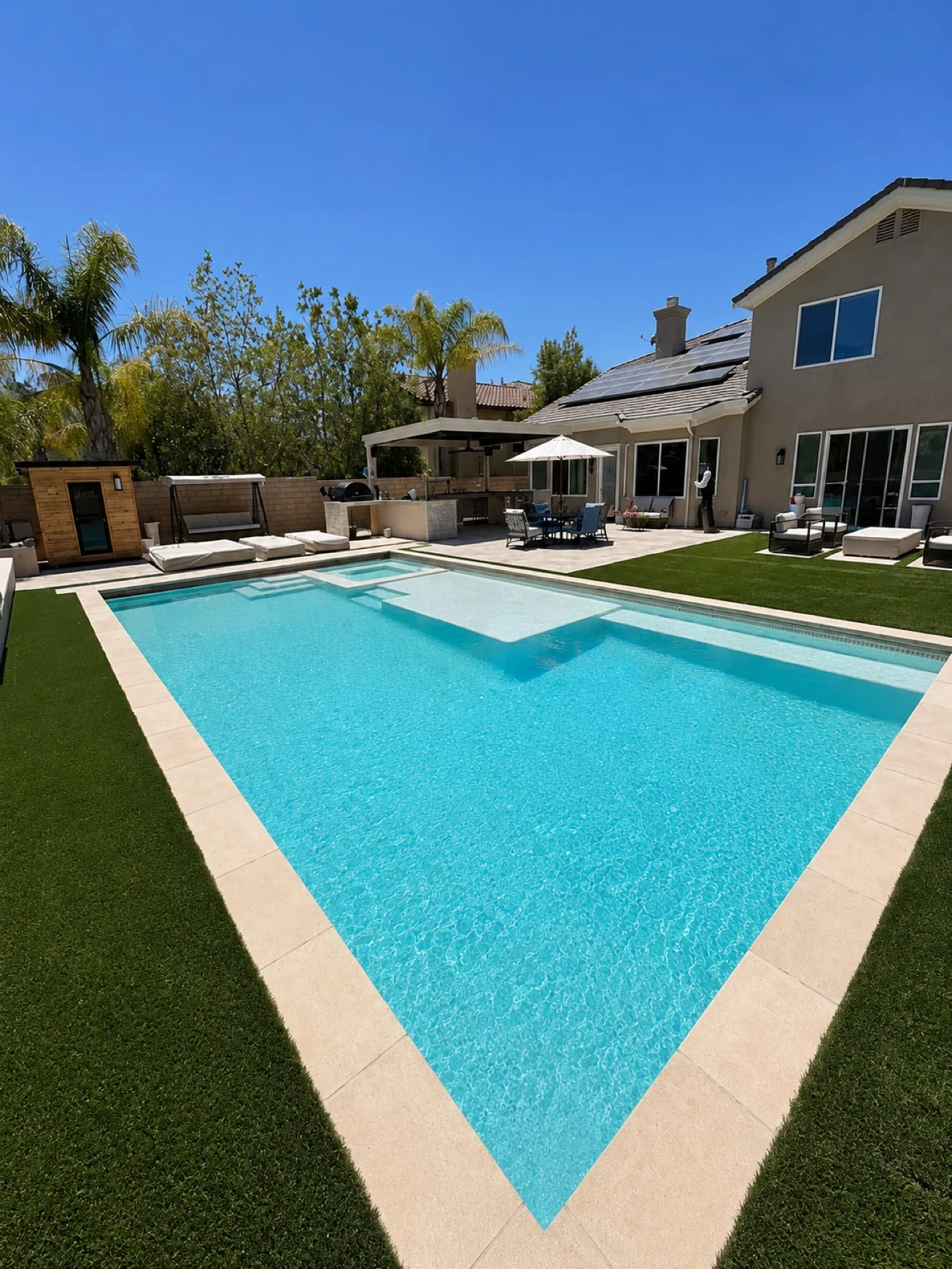Pool with Baja shelf and covered patio by Moda Outdoor Living in Santa Clarita, CA — luxury outdoor living design and build