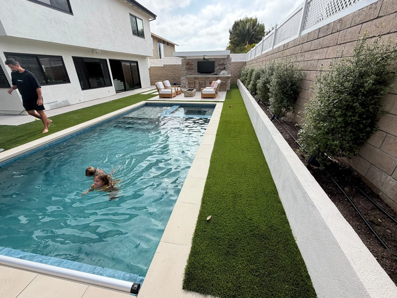 Lap pool with turf border and theater wall by Moda Outdoor Living in Huntington Beach, CA — luxury outdoor living design and build