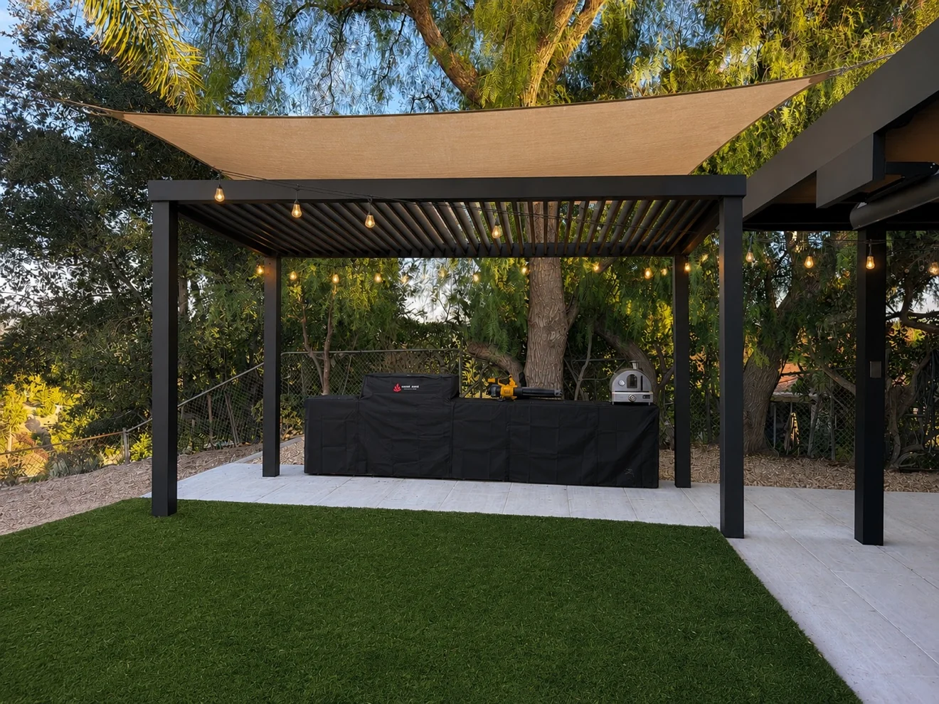 Pergola with shade sail and string lights by Moda Outdoor Living in West Hills, CA — luxury outdoor living design and build