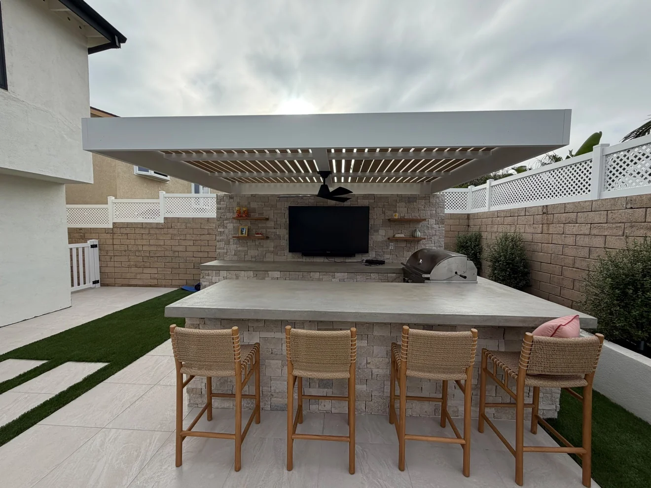 Covered bar with TV and stone counter by Moda Outdoor Living in Huntington Beach, CA — luxury outdoor living design and build