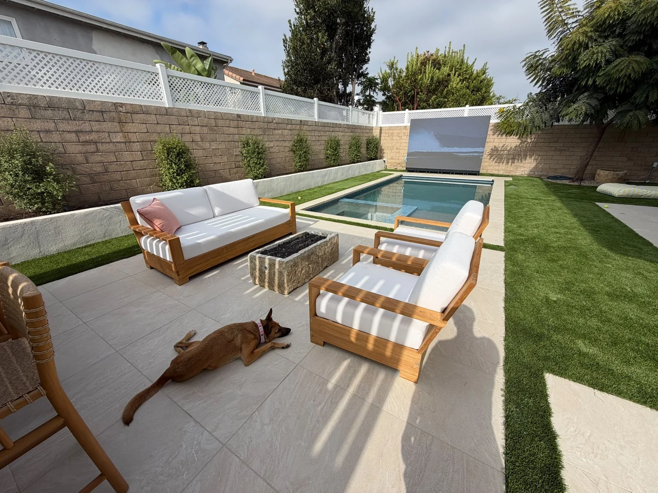 Lounge and fire pit facing the theater wall by Moda Outdoor Living in Huntington Beach, CA — luxury outdoor living design and build