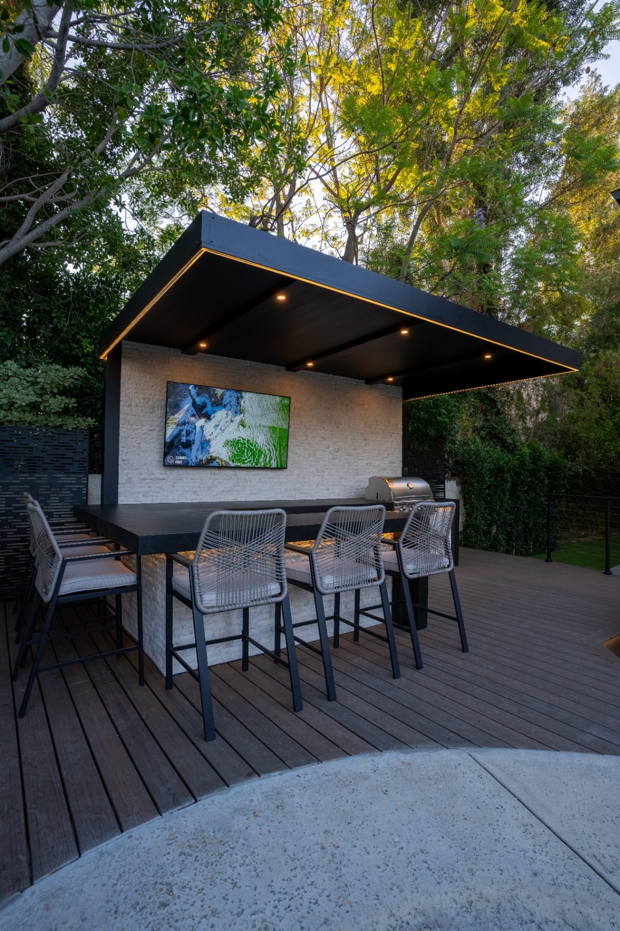 Hillside retaining wall with pool and pavers at dusk - Moda Outdoor Living
