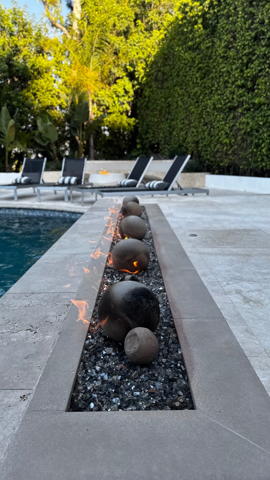 Linear fire feature with fire glass along modern pool edge