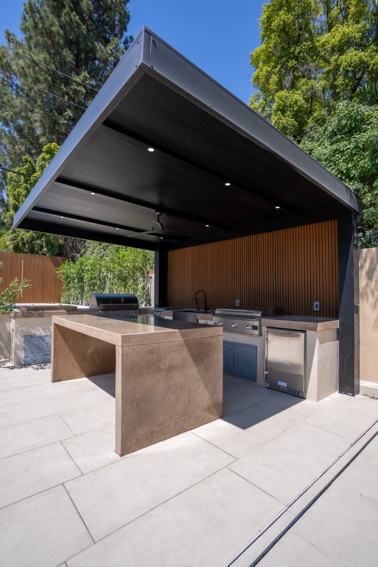 Modern outdoor kitchen under pergola with cooking features