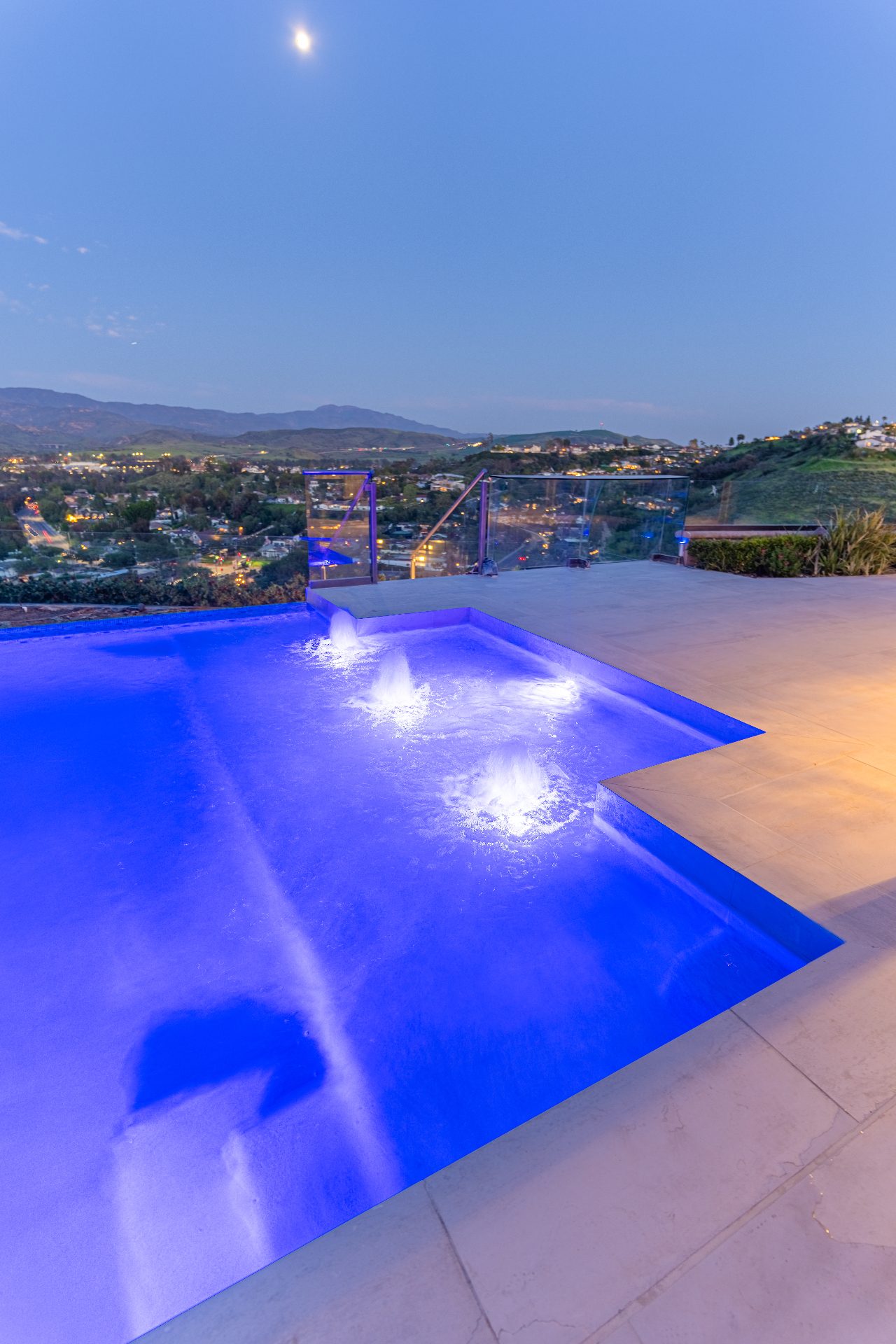 Trending outdoor living space with pool, fire features, and modern lounge furniture at sunset
