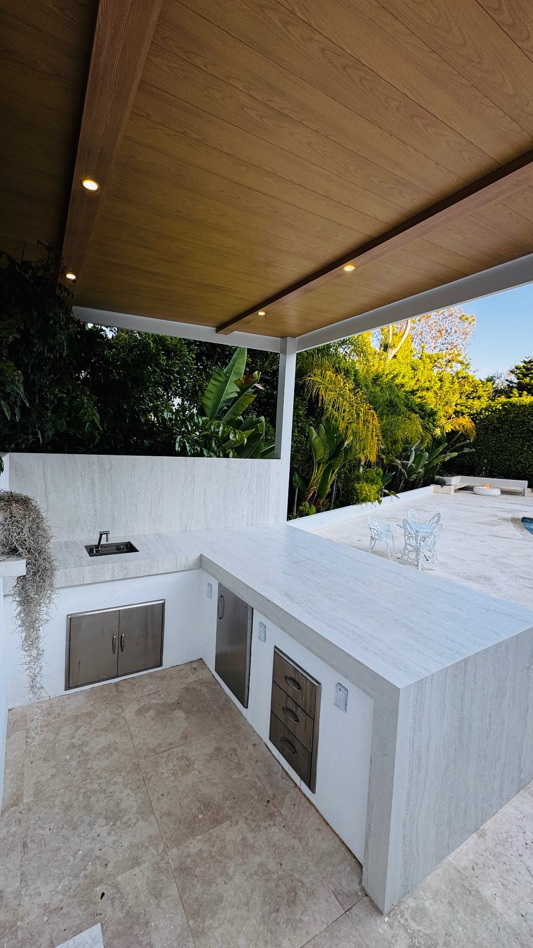 White outdoor kitchen with integrated bar seating area