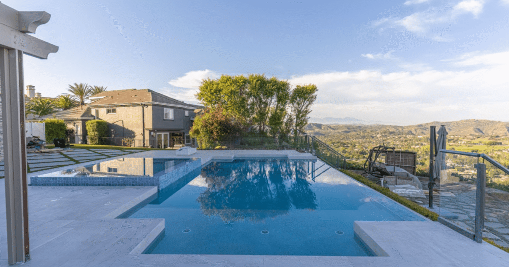 Luxury pool with Baja shelf, LED lighting, and water features, showcasing popular custom add-ons for a high-end backyard