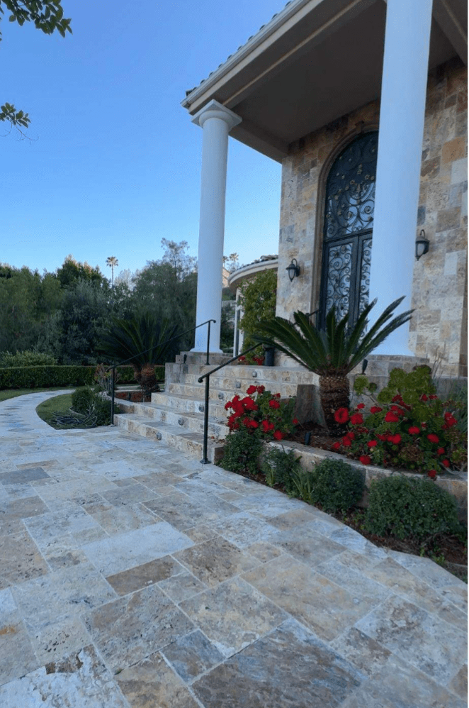 Backyard patio with natural stone pavers in organic shapes and earthy tones, creating a high-end, timeless outdoor look