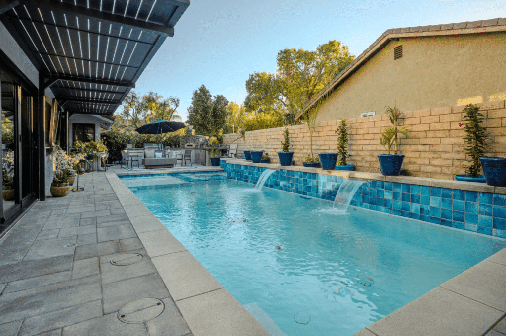 Modern backyard pool with built-in Baja shelf, fire feature, and clean landscaping — example of thoughtful pool design that avoids common homeowner mistakes.