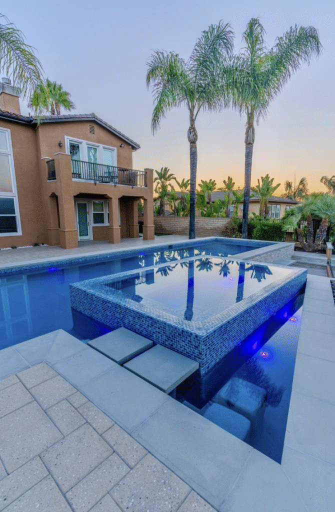 Backyard pool illuminated with underwater LED lights and surrounding landscape lighting, enhancing evening ambiance and safety
